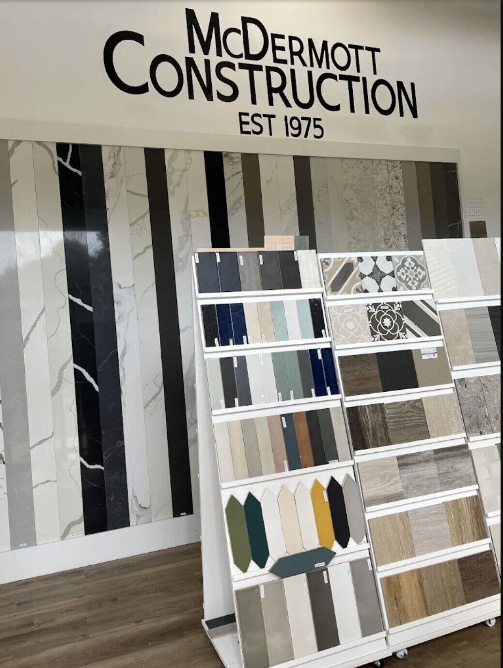 The McDermott Construction showroom — a full wall of stone, tile, and flooring samples beneath the McDermott Construction, Est. 1975 sign