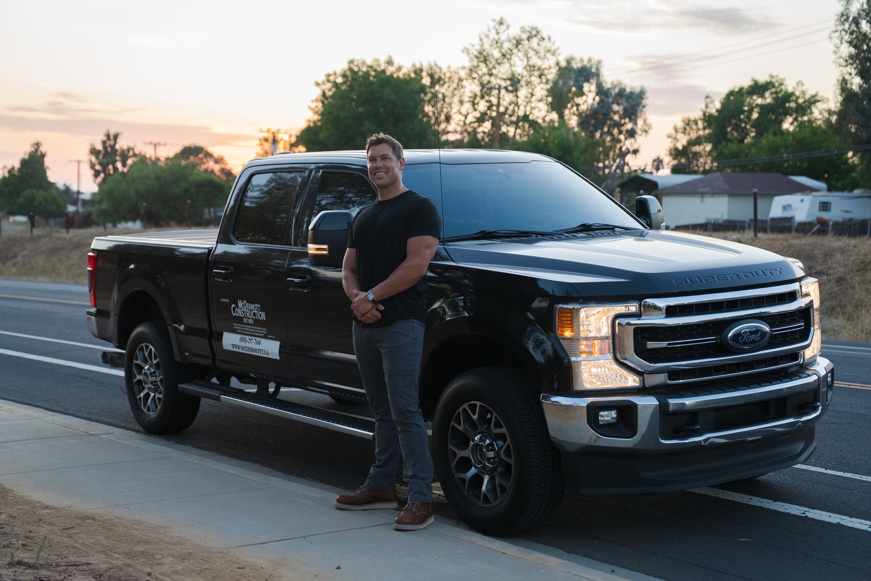 Sean McDermott beside the McDermott Construction truck at sunset